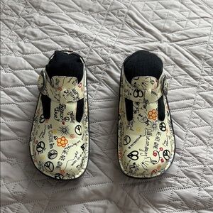 Alegria Beige and Black peace and love t strap clogs.